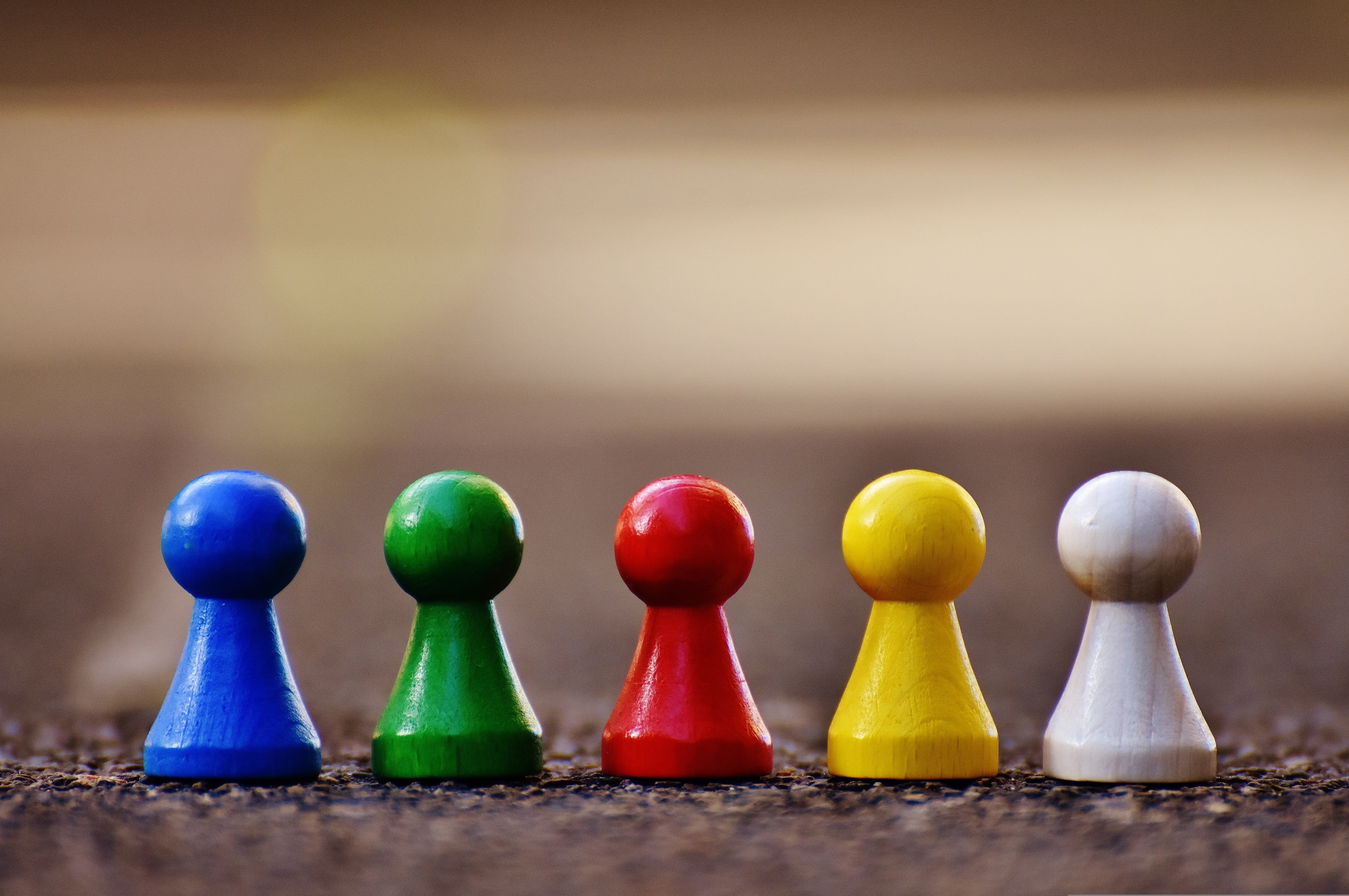 Fem spillebrikker i treverk stående ved siden av hverandre, i ulike farger.