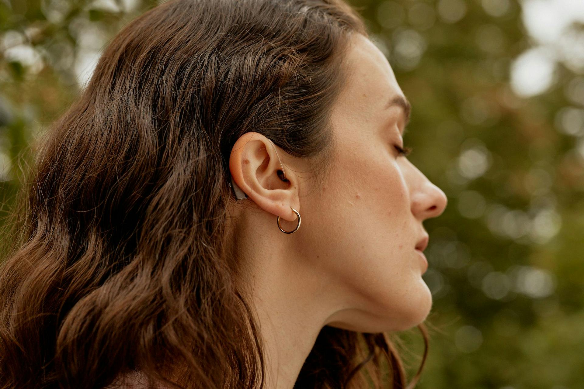 Mørkhåret kvinne i profil med synlig høreapparat