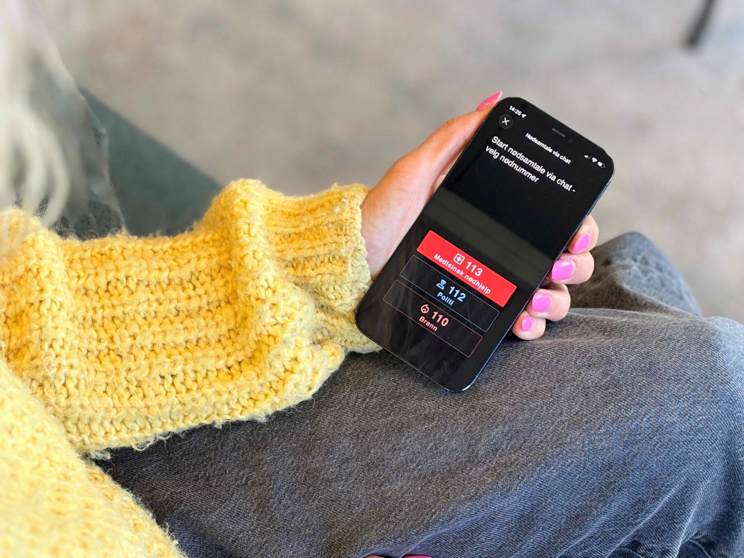 Nærbilde av en mobiltelefon der skjermen viser ikoner med de tre nødnumrene 113, 112 og 110, og spørsmpl om man vil starte en nødchat.